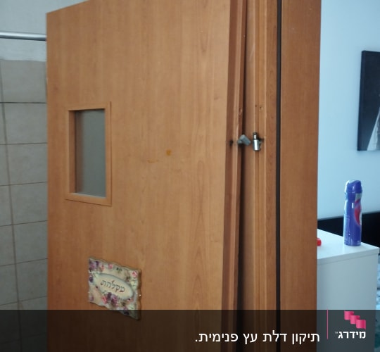 דלת עץ עם חלון קטן ושלט פרחים
